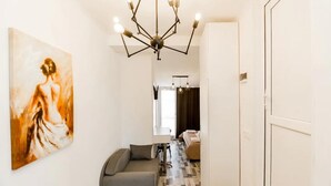 Una habitación de hotel con una lámpara de araña moderna, un sofá, una mesa de comedor y un cuadro en la pared.