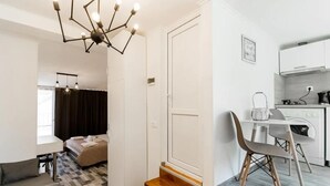 Una habitación de hotel moderna con cama, escritorio, silla, mesa de comedor con sillas, zona de cocina y una escalera.