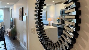 A modern kitchen with a central island, a dining area with a wooden table and chairs, and a large mirror on the wall. - Halifax waterfront 2 BR/2 Bath with 6 appliances (Halifax)