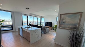 A modern apartment with a kitchen island, dining area, and living room with a TV. - Waterview 2 BR / 2 Bath penthouse in Northend HFX. (Halifax)