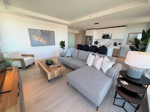 Una sala moderna con un sofá gris, una mesa de centro de madera y un comedor con una mesa de madera.