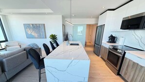 A modern kitchen with a marble island, stainless steel appliances, and a dining area with a sofa and chairs. - Waterview 2 BR / 2 Bath penthouse in Northend HFX. (Halifax)