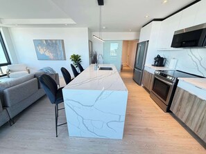 Una cocina moderna con una isla de mármol, electrodomésticos de acero inoxidable y un comedor con sofá y sillas.