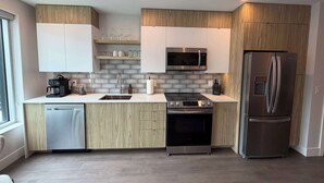 Een moderne keuken met een vaatwasser, fornuis, magnetron en koelkast.