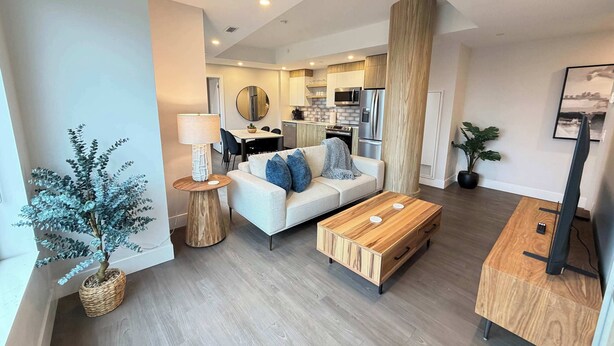 A modern living room with a sofa, coffee table, and a dining area with chairs. - Downtown Waterview, 2 BR/2 Bath with 6 appliances (Halifax)