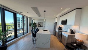A modern kitchen with a marble island, stainless steel appliances, and large windows offering a city view. - Northend HFX 2 BR/ 2 Bath Penthouse with waterview (Halifax)