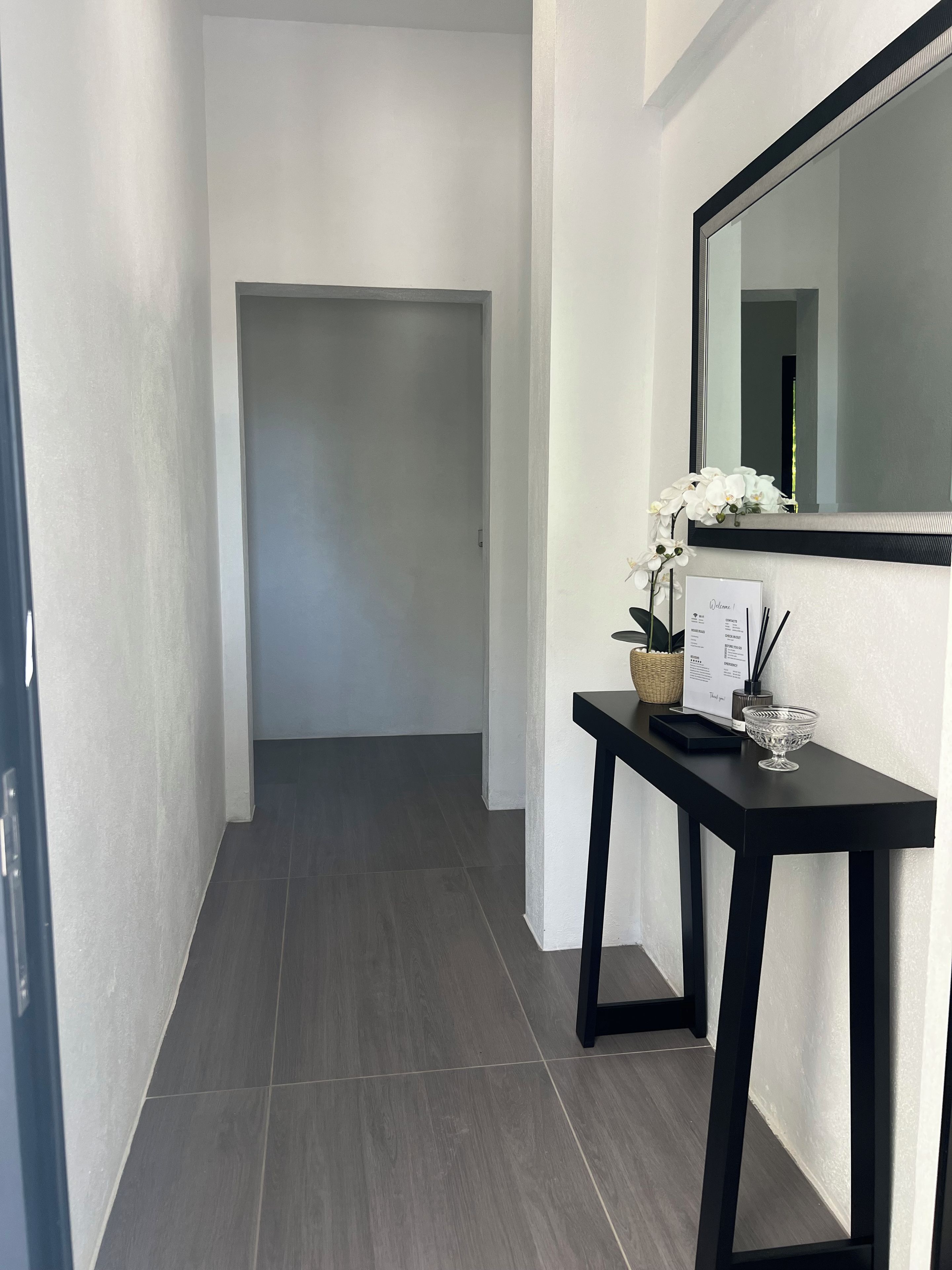 A hallway with a black console table, a mirror, and a door leading to another room.
