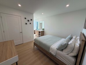 Ein Schlafzimmer mit Bett, Kommode, Spiegel und Tür.