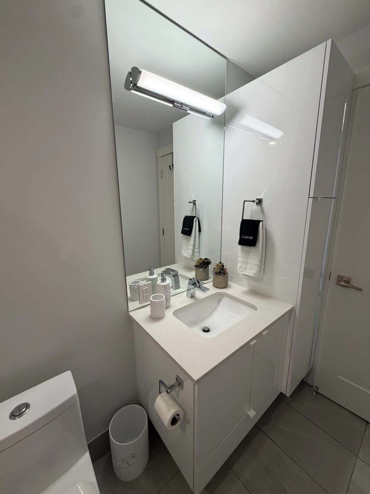 Une salle de bain moderne avec un lavabo blanc, un miroir et des toilettes.