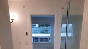 Um banheiro moderno com box de vidro, pia embutida e vista para a varanda externa.