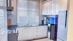 A kitchen with white cabinets, a stainless steel refrigerator, a microwave, and a water dispenser. - Metra Tower (Phnom Penh)