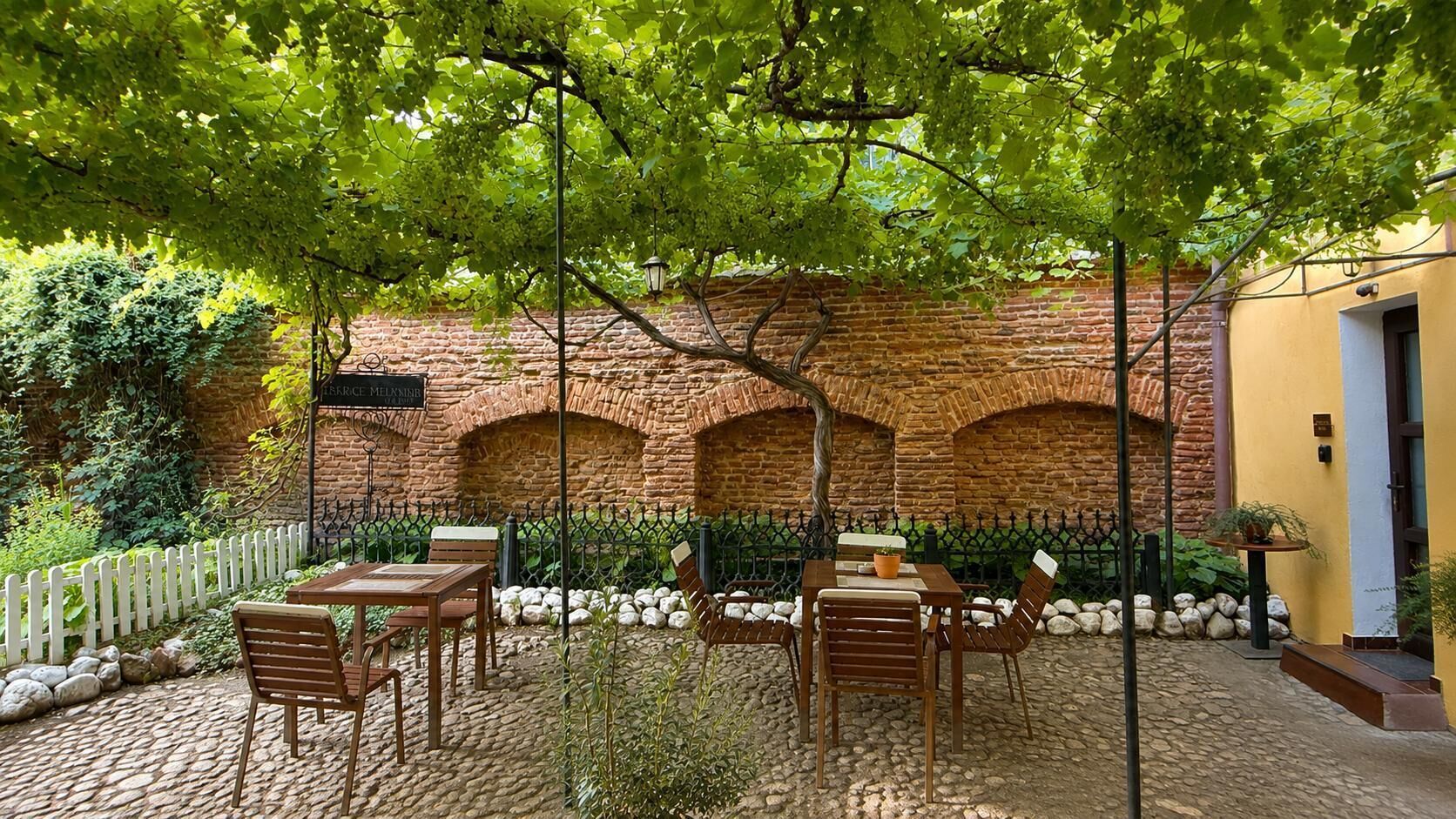 Eine Außenpatio mit Ziegelmauern, Steinböden und Holzmöbeln.