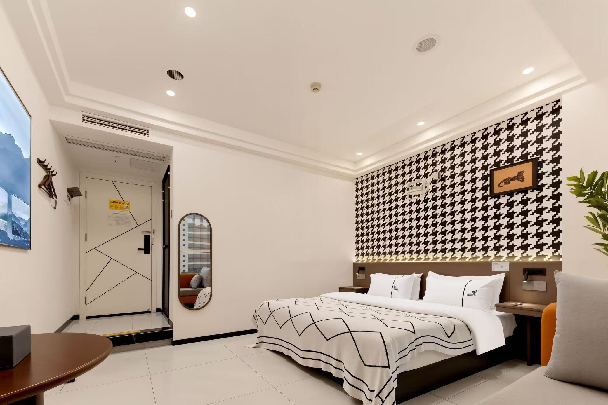 A modern hotel room with a bed, a desk, and a mirror.