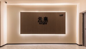 A modern interior with a wooden wall panel displaying '元来 origin' and a door marked '10F'.
