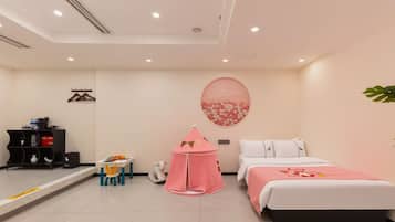 A bedroom with a bed, a small table with toys, a pink play tent, and a wall decoration.