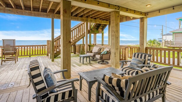 A wooden deck with outdoor furniture, a staircase, and a view of the ocean. - All BEACH! 2nd row w/full views, Sleeps 16, FUN! (Bolivar Peninsula)