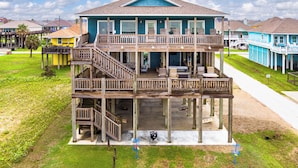 A two-story beachfront house with a balcony, outdoor seating, and a visible deck area. - All BEACH! 2nd row w/full views, Sleeps 16, FUN! (Bolivar Peninsula)