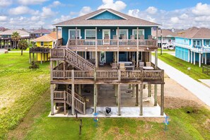 A two-story beachfront house with a balcony, outdoor seating, and a visible deck area. - All BEACH! 2nd row w/full views, Sleeps 16, FUN! (Bolivar Peninsula)