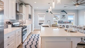 A modern kitchen with white cabinetry, a central island, pendant lights, and a ceiling fan. - All BEACH! 2nd row w/full views, Sleeps 16, FUN! (Bolivar Peninsula)