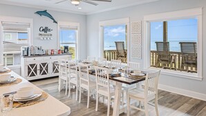 A dining area with a view of the ocean, a ceiling fan, and a kitchen with coffee-making equipment. - All BEACH! 2nd row w/full views, Sleeps 16, FUN! (Bolivar Peninsula)
