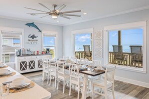 A dining area with a view of the ocean, a ceiling fan, and a kitchen with coffee-making equipment. - All BEACH! 2nd row w/full views, Sleeps 16, FUN! (Bolivar Peninsula)