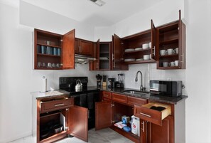 Una cocina con gabinetes de madera, estufa, fregadero y microondas.