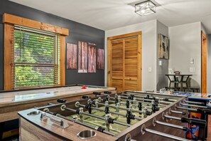 A room with a foosball table, wooden doors, and artwork on the walls. - Bryson City Cabin, Game Loft, Hot Tub, Fire Pit (Bryson City)