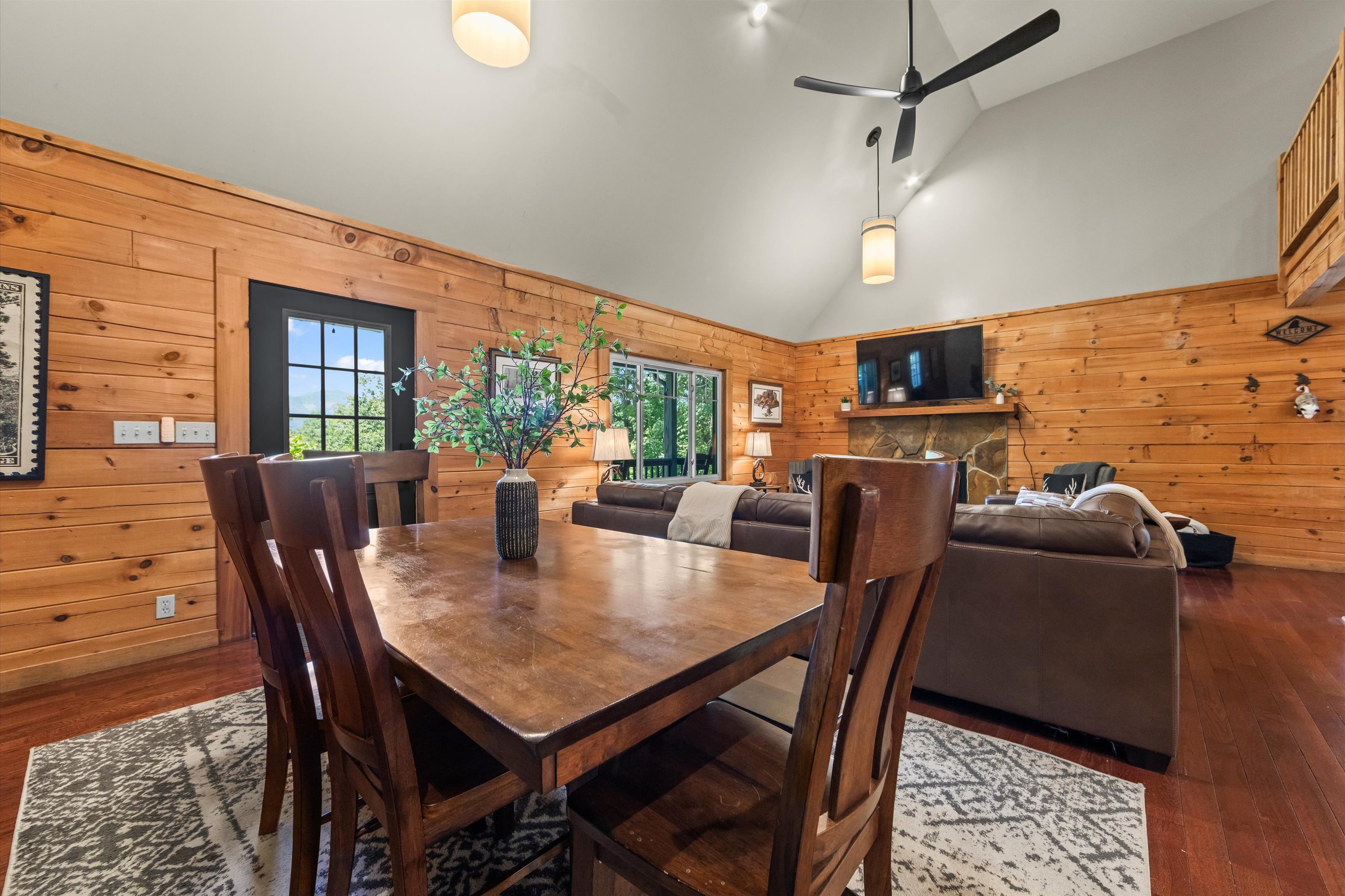 Un interior de madera con una mesa de comedor, sillas, un sofá y un televisor.