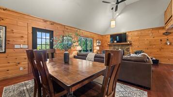 Un interior de madera con una mesa de comedor, sillas, un sofá y un televisor.