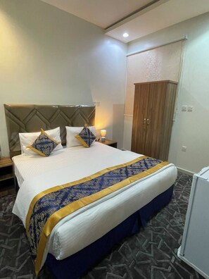 A hotel room with a bed, a wardrobe, a nightstand, and a lamp. - Quiet Rooms 5   (Riyadh)