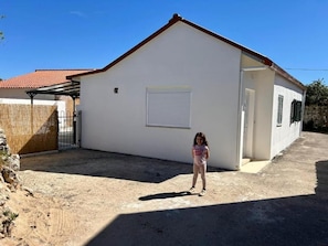 A single-story building with a white exterior, a red-tiled roof, and a closed shutter door. - Villa Carmel - Private Camino de Santigo House in Rabaçal (Penela)