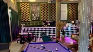 Ein Billardtisch mit Kugeln, eine Bar und eine Sitzgruppe.