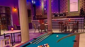 Ein Billardtisch mit Kugeln, eine Bar und Sitzgelegenheiten.