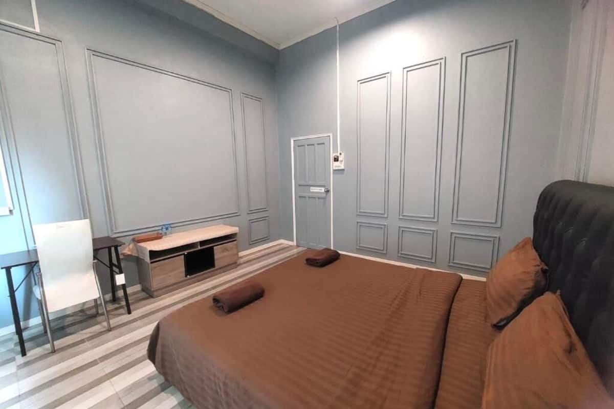 A bedroom with a bed, a desk, and a chair.