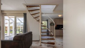 Un interior modern amb una escala espiraltra, un sofà i una zona de cuina.