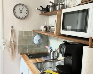 Eine Küche mit Mikrowelle, Herd, Spüle und einem hängenden Sieb.