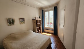 Ein Schlafzimmer mit einem Bett, einer Holzwandregal und einem Fenster mit Vorhängen.