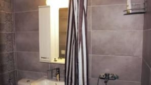 Un bagno con lavandino, specchio e tenda da doccia.