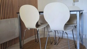 A room with a wooden slatted wall, a white table with two white chairs, a telephone, and a woven rug on the floor. - Apartment parcs de grimaud (Grimaud)