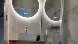 A modern bathroom with a wooden vanity, a sink, and two round mirrors. - Apartment parcs de grimaud (Grimaud)