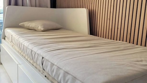 A modern bed with a headboard, a pillow, and a wooden slat wall behind it. - Apartment parcs de grimaud (Grimaud)