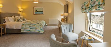 A bedroom with a bed, a desk, a chair, a radiator, and a window with a view.