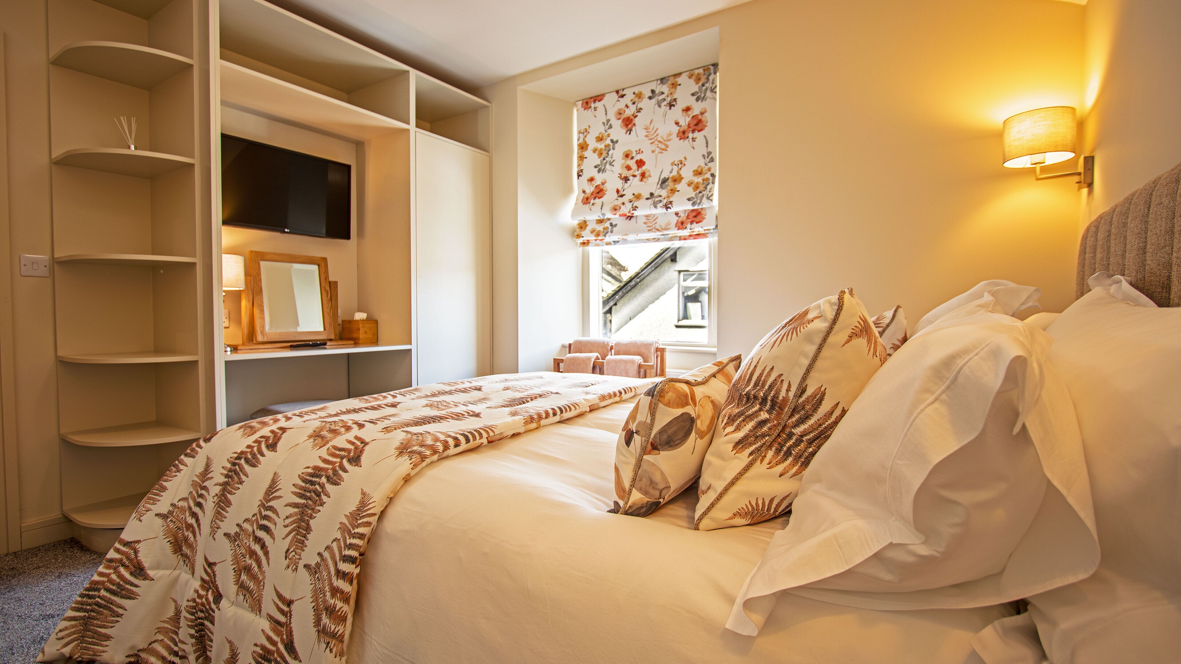 A bedroom with a bed, a wardrobe, a window with a view, and a wall-mounted lamp.