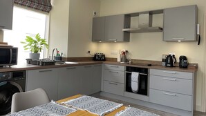 Eine moderne Küche mit grauen Schränken, einer Mikrowelle, einem Toaster, einem Wasserkocher und einer Kaffeemaschine.