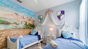Une chambre avec deux lits, un mur en pierre, une fresque murale et une table de chevet avec une lampe.