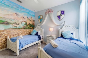 Ein Schlafzimmer mit zwei Betten, einer Steinwand, einem Wandbild und einem Nachttisch mit Lampe.