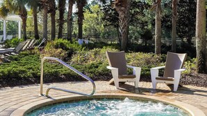 Un bain à remous entouré de chaises longues et bordé d’une terrasse en briques.