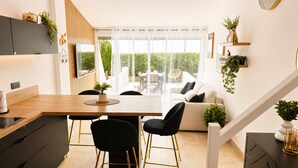A modern kitchen with a dining area, a staircase, and a living room with a sofa and plants. - Naturiste Cap d'Agde Villa Héliovillage 23 (Agde)