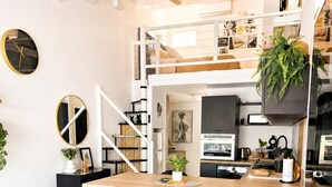 A modern kitchen with a central island, black bar stools, a ceiling fan, and a staircase leading to an upper level. - Naturiste Cap d'Agde Villa Héliovillage 23 (Agde)