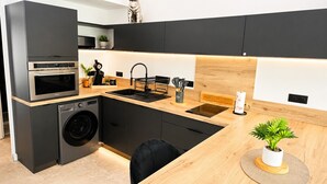 A modern kitchen with a built-in washing machine, a microwave, and a sink. - Naturiste Cap d'Agde Villa Héliovillage 23 (Agde)